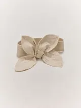 Faja de lino y algodón color beige con diseño regulable, adornada con detalles en forma de pétalos con bordados pespunteados y bordes deshilachados.