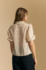 Camisa blanca de manga corta abullonada con terminación elastizada y cuello con leve frunce. Presenta una estampa floral integral.