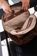 Mochila de cuero genuino color marrón, con diseño minimalista, compartimento principal con cierre, bolsillo frontal con etiqueta de marca y correas ajustables.