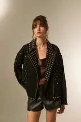 Campera de jean negra con tachas plateadas en el cuello, solapas y parte delantera. Tiene cierre asimétrico, bolsillos laterales con cierre y puños con cierre.