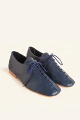 Zapato tipo oxford plano de cuero vacuno en color azul marino, con cordones al tono y suela de cuero.
