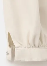 Pantalón jeans estilo balloon de tiro medio y largo tobillero, confeccionado en 100% algodón. Presenta detalle de pinzas en la cintura, dos bolsillos laterales, cierre de gancho y cremallera, y puños elásticos en los tobillos.