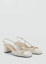 Zapato tipo slingback color blanco con tacón bloque de 5 cm, punta cuadrada y detalle de eslabones dorados en el empeine. Cuenta con cierre de hebilla ajustable en la tira trasera.