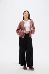 Saco de punto con textura, color rosado, con cuello a la base, cierre frontal con botones y detalle de cordón para anudar en el cuello. Presenta mangas largas con puños ajustados.