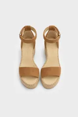 Sandalias de tacón en cuña forrada en yute trenzado, con capellada de cuero negro, tira en el talón y tira ajustable al tobillo con hebilla metálica.
