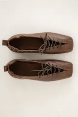 Mocasín marrón de cuero, con cordones frontales y diseño de corte bajo.
