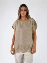 Blusa de lino color beige, con mangas cortas y detalle de encaje en el borde inferior.