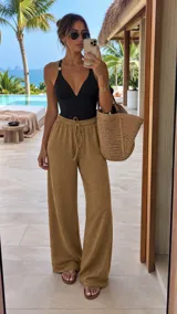 Pantalón tipo palazzo de tiro alto con cintura elástica y cordón ajustable. Confeccionado en tela texturizada con caída fluida y corte amplio.