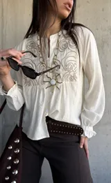Camisa de lino color natural, con calce relajado, mangas largas amplias con puños fruncidos y delicado bordado geométrico en el frente.
