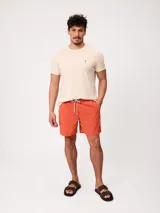 Short de baño Polanco modelo Loraz, color coral, con cintura elástica, cordón ajustable blanco y negro, bolsillos laterales y pequeño logo circular estampado en la pierna.