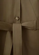 Chaqueta de gabardina color verde militar, de corte oversize con cuello alto abotonado de manera asimétrica, mangas largas con puños ajustables y cinturón ajustable del mismo tejido.