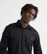 Camisa verde militar de manga larga en sarga de algodón, con cuello clásico, cierre frontal abotonado y dos bolsillos con solapa abotonada en el pecho.