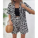 Conjunto de dos piezas compuesto por una camisa de manga corta con cuello italiano y cierre frontal de botones, y un short con cintura elástica y bolsillos laterales. Ambas prendas presentan un diseño estampado de animal print.