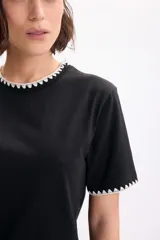 Camiseta de manga corta negra con detalles de pespuntes blancos en contraste en el cuello redondo y en los bordes de las mangas.