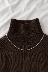 Collar de cuentas pequeñas transparentes con una sección central de cuentas doradas.