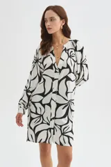 Camisa tipo vestido de viscosa con estampado floral abstracto en blanco y negro, cuello en V con botonera frontal completa, mangas largas abullonadas y diseño holgado.