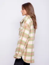 Sobrecamisa a cuadros color verde, beige y rosa, de tela tipo corderito, con cuello camisero, cierre frontal con botones y dos bolsillos con solapa en el pecho.