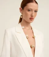 Conjunto de accesorios compuesto por un collar largo y un par de aros colgantes. El diseño presenta esferas de acabado dorado y perlas blancas intercaladas a lo largo de una cadena fina metálica.