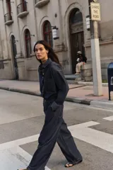 Camisa amplia de denim azul oscuro con cuello solapa, manga larga, bolsillo de plastrón en el pecho y cierre frontal con botones a presión dorados.