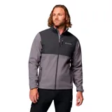 Campera softshell Columbia para hombre, resistente al agua y al viento. Presenta un diseño bicolor en tonos gris oscuro y gris medio, con cierre frontal completo, cuello alto con protector de mentón, bolsillos laterales y un bolsillo en el pecho con cierre. Incluye puños ajustables y dobladillo con ceñidor.