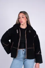 Campera de corderito color beige con ribetes y detalles en símil cuero marrón, cuello alto con hebilla decorativa, bolsillos laterales y cierre frontal.