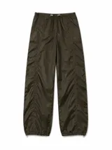 Pantalon estilo parachute de tela técnica con acabado arrugado, cintura elástica con cordón ajustable y bajos con cordón regulable. Presenta costuras laterales fruncidas que aportan volumen y un corte holgado.
