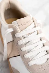 Zapatillas bajas de cuero color blanco y beige con suela marrón y detalle animal print en el talón.