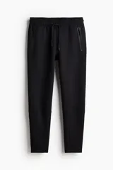 Jogger deportivo negro de corte ajustado, confeccionado en tejido funcional DryMove™ que absorbe el sudor. Presenta cintura elástica con cordón de ajuste, bolsillos laterales con cierre sellado y piernas ajustadas.