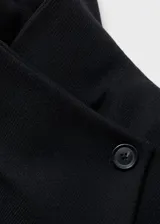 Abrigo largo de paño en color negro, con cuello chimenea y cierre frontal con botones y cinturón de lazo ajustable. Presenta diseño recto, manga larga y bolsillos laterales.