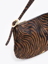 Cartera tipo hobo confeccionada en cuero con pelo vacuno estampado animal print. Presenta correa de hombro ajustable con detalles de hebillas metálicas en los laterales y cierre superior.