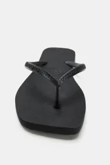 Sandalias planas de dedo tipo ojota, color negro, con diseño minimalista y suela de goma con textura en relieve.