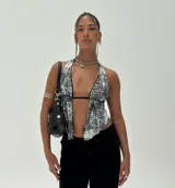 Top halter ajustado con estampado abstracto en blanco y negro, con escote profundo en V y bajo asimétrico. Se ata al cuello y tiene un detalle de tirante fino negro debajo del busto.