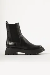 Bota tipo Chelsea de cuero negro con paneles elásticos laterales y suela track dentada de goma.