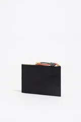 Billetera de estructura blanda confeccionada en nylon negro, con cierre de cremallera superior y bolsillo frontal con cierre. Presenta logo metálico dorado en el frente.