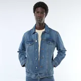 Chaqueta vaquera de corte clásico en color azul, con cierre frontal de botones metálicos, bolsillos frontales con solapa en el pecho y bolsillos ribeteados en los laterales.