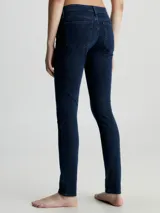 Jeans ajustados de mezclilla elástica color azul oscuro puro, con tiro medio y pierna estrecha. Presentan un diseño clásico de cinco bolsillos y bragueta con cremallera.