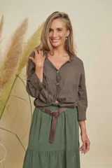 Camisa de algodón color verde militar, con cuello camisero, botones frontales y mangas largas. La parte inferior está anudada al frente.