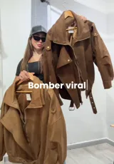 Campera tipo bomber de gamuza con cierre frontal, cuello solapa, detalles de botones metálicos y cinturón ajustable en la cintura.