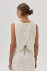 Top de lentejuelas color blanco, sin mangas y con espalda cruzada.