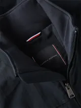 Chaleco azul marino Tommy Hilfiger de cuello alto, con cierre de cremallera frontal, bolsillos laterales de ojal y logo de la marca bordado en rojo en el pecho.