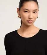 Suéter de punto acanalado color beige, con cuello redondo y mangas largas. Confeccionado en tejido tricot con textura suave y ajuste al cuerpo.