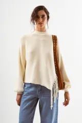 Sweater negro de tejido acanalado, con cuello redondo y un detalle asimétrico en el ruedo inferior con flecos largos.