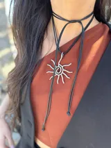 Collar con cordón ajustable color beige y dije de sol plateado.