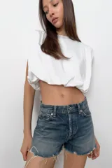 Top de algodón con cuello redondo, diseño sin mangas con hombreras marcadas y detalle de pliegues. Presenta un bajo acabado tipo globo con elástico.
