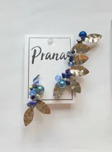 Par de aros trepadores con cuentas de colores azules y plateadas, y dijes de metal con forma de hoja.