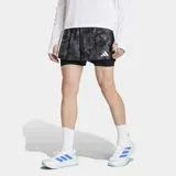 Short deportivo 2 en 1 Adidas con calza interior integrada. Presenta un diseño estampado con efecto spray en tonos grises y negros, cintura elástica con cordón de ajuste y logo de la marca en el lateral. Incluye bolsillos funcionales y tecnología Formotion para mayor libertad de movimiento.