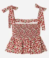 Blusa de viscosa y lino con estampado floral en tonos rojos y blancos. Presenta escote cuadrado, cuerpo ajustado con fruncido en la cintura y bajo con volado (peplum). Los breteles son anchos y se atan con lazos en los hombros.