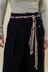 Pantalón wide leg de tiro alto en color negro, con diseño de pinzas delanteras que aportan volumen y caída fluida. Incluye bolsillos laterales y un lazo desmontable en la cintura que combina cordón con cinta de estampado animal print.