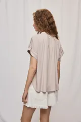 Camisa de manga corta color celeste, confeccionada en viscosa fluida, con silueta amplia y escote redondo con frunces y lazo para anudar.