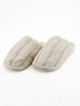 Pantuflas de estar por casa tipo chinela, confeccionadas en tela de peluche suave color crudo, con diseño acolchado de franjas verticales y suela plana.